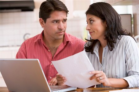 Couple in kitchen with paperwork using laptop looking unhappy Stock Photo - Budget Royalty-Free & Subscription, Code: 400-04043669