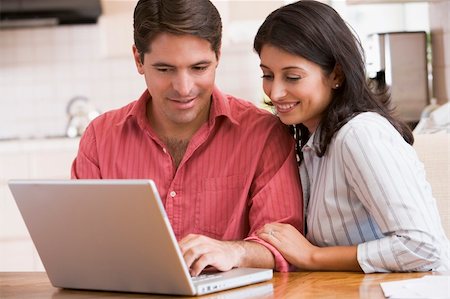 Couple in kitchen with laptop smiling Stock Photo - Budget Royalty-Free & Subscription, Code: 400-04043732