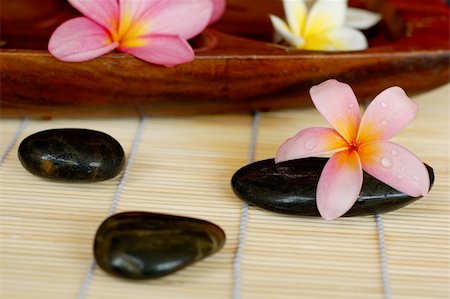 simsearch:400-05282502,k - Frangipani and plumerias and black massage stones placed on bamboo mate at spa. Photographie de stock - Aubaine LD & Abonnement, Code: 400-04054995