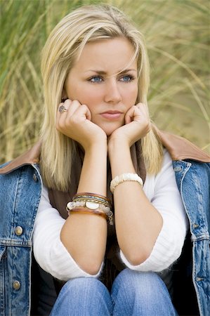 simsearch:400-04047186,k - A beautiful blond haired blue eyed model sits thinking amid tall green grass Stock Photo - Budget Royalty-Free & Subscription, Code: 400-04058930