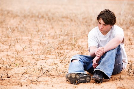 sascha (artist) - teenager sitting depressed in dry lakebed amongst the weeds, contemplating. Fotografie stock - Microstock e Abbonamento, Codice: 400-04059430