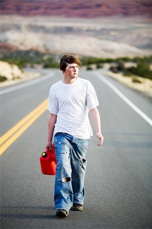 sascha (artist) - out of gas - male teenager with gas can walking on a mountain road in late sun Fotografie stock - Microstock e Abbonamento, Codice: 400-04059443