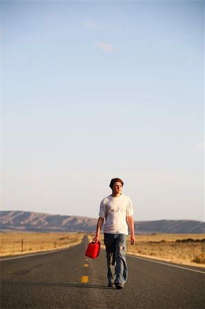 sascha (artist) - out of gas - male teenager walking down the highway with empty gas can. Blue sky with ample copyspace. Fotografie stock - Microstock e Abbonamento, Codice: 400-04059770