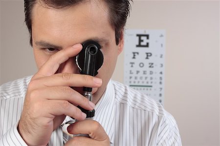 sehtafel - An optometrist turning the lens dial of the opthalmoscope while examining a patient's eyes. Stockbilder - Microstock & Abonnement, Bildnummer: 400-04059800