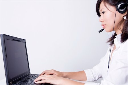 simsearch:400-05209692,k - Asian consultants with headsets working on laptop computer on grey background. Stock Photo - Budget Royalty-Free & Subscription, Code: 400-04052895