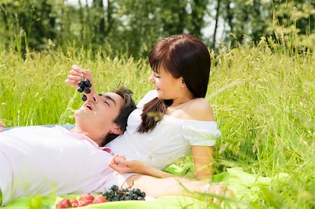 picture of the black man feeding the woman fruit - Couple lying in grass, smiling and eating grapes Foto de stock - Super Valor sin royalties y Suscripción, Código: 400-04066408