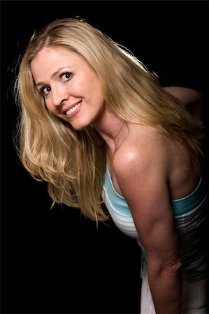 simsearch:400-04498992,k - Attractive fashion photo of a woman with long blond hair with a nice smile leaning forward over black with a back light Photographie de stock - Aubaine LD & Abonnement, Code: 400-04066739