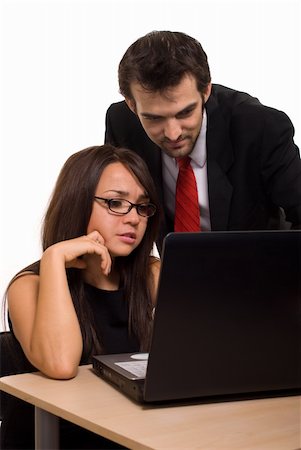 Two business people wearing black business attire attractive brunette woman with eyeglasses and one man with red tie woman sitting at desk in front of computer with man leaning over both looking at screen Stock Photo - Budget Royalty-Free & Subscription, Code: 400-04068762