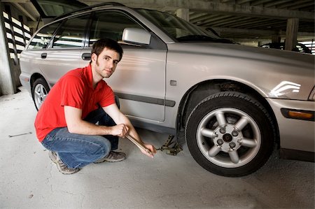 simsearch:400-04561871,k - A male in a red shirt changing the front tire on a car Foto de stock - Super Valor sin royalties y Suscripción, Código: 400-04061389