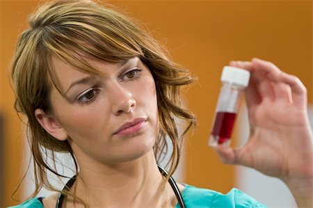 A pretty young female doctor in scrubs with a stethoscope examines a blood sample intently Stock Photo - Budget Royalty-Free & Subscription, Code: 400-04063844