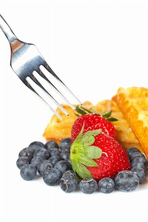 simsearch:400-08110674,k - Waffles, blueberries and the fork pricking the strawberry on white background. Shallow depth of field Stockbilder - Microstock & Abonnement, Bildnummer: 400-04063876