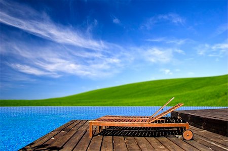 Beautiful outdoor space with a chair beside the pool and a beautiful green meadow  in the background Stock Photo - Budget Royalty-Free & Subscription, Code: 400-04071863