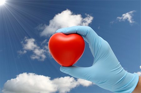 hand in latex blue gloves holding a toy heart under a blue sky Stock Photo - Budget Royalty-Free & Subscription, Code: 400-04073002