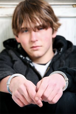 youth crime - teenage in handcuffs against wall. Focus on handcuffs. Foto de stock - Super Valor sin royalties y Suscripción, Código: 400-04073551