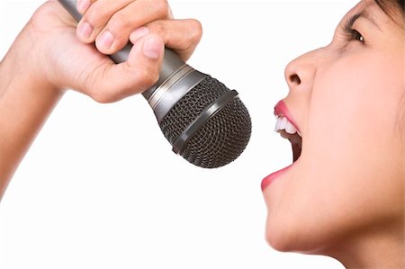 A woman is singing loudly with a microphone holding higher than her face, shot against white background. small depth of field Stock Photo - Budget Royalty-Free & Subscription, Code: 400-04082412