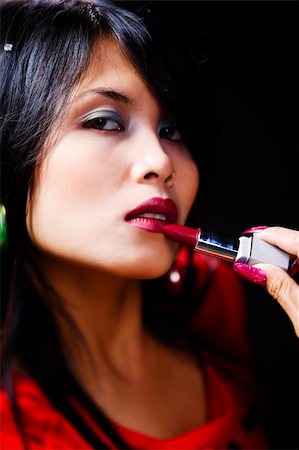 A young Asian woman using red lipstick. Very contrast, shallow depth of field against dark room. Stock Photo - Budget Royalty-Free & Subscription, Code: 400-04082421