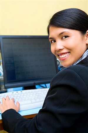 Happy businesswoman facing the camera while working on her computer in office. Stock Photo - Budget Royalty-Free & Subscription, Code: 400-04082475