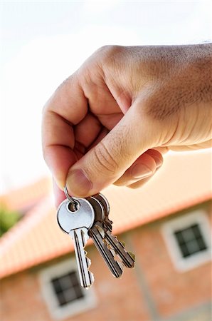 Man's hand holding keys with a house under construction in background Stock Photo - Budget Royalty-Free & Subscription, Code: 400-04093653