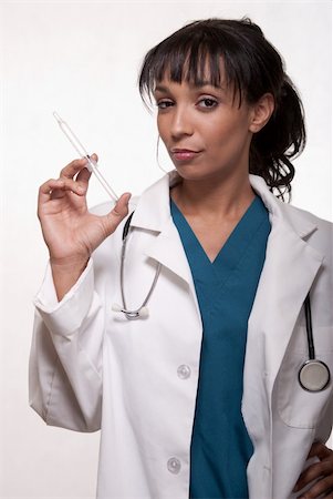 simsearch:400-03995908,k - Attractive brunette woman healthcare worker wearing blue scrubs and a stethoscope holding up a syringe or needle Stock Photo - Budget Royalty-Free & Subscription, Code: 400-04107363