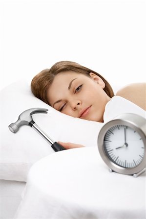 The girl lies in bed and is going to break a hammer an alarm clock Stock Photo - Budget Royalty-Free & Subscription, Code: 400-04107841