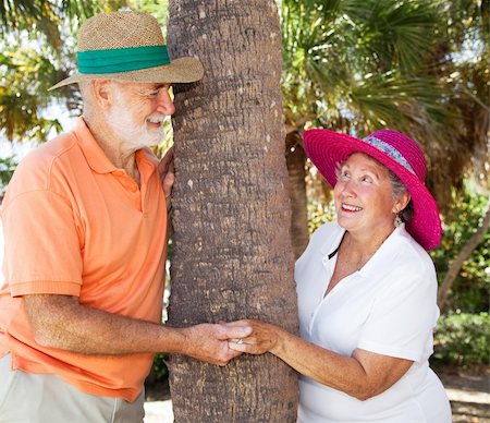 simsearch:400-04109826,k - Senior couple in love, flirting with each other as they peek around a tree. Fotografie stock - Microstock e Abbonamento, Codice: 400-04108003