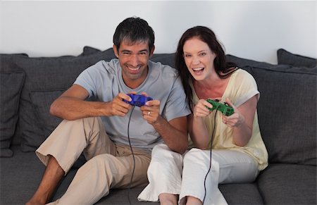 simsearch:400-05195435,k - Young Couple on Sofa Playing Video Games Stockbilder - Microstock & Abonnement, Bildnummer: 400-04108751