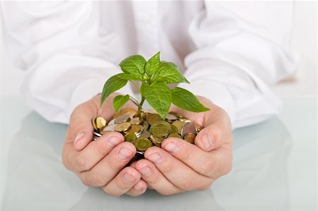 pile hands bussiness - Business man holding young plant rising from a pile of coins - good investment and savings concept Stock Photo - Budget Royalty-Free & Subscription, Code: 400-04102758