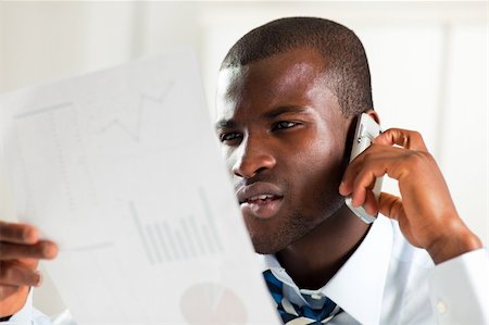 simsearch:400-04238062,k - young adult afro-american businessman examining charts and talking on the phone Photographie de stock - Aubaine LD & Abonnement, Code: 400-04115041