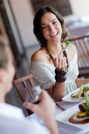 eastwestimaging (artist) - A young woman laughing whilst eating dinner at a restaurant Foto de stock - Super Valor sin royalties y Suscripción, Código: 400-04116666