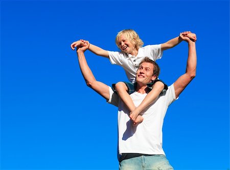 Boy giving kid a piggyback ride against the blue sky Stock Photo - Budget Royalty-Free & Subscription, Code: 400-04118335