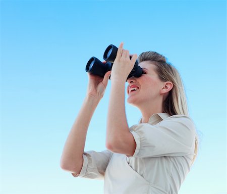 simsearch:400-04632747,k - Blonde businesswoman looking through binoculars against blue sky Fotografie stock - Microstock e Abbonamento, Codice: 400-04118389