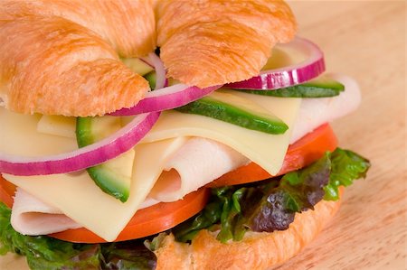 Turkey sandwich on a croissant with swiss cheese, avocado, tomatoes, lettuce, and onion. Stock Photo - Budget Royalty-Free & Subscription, Code: 400-04118750