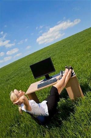 relaxed attractive woman feet up - Business concept shot of a beautiful young woman relaxing at a desk in a green field with a bright blue sky. Shot on location. Photographie de stock - Aubaine LD & Abonnement, Code: 400-04119055