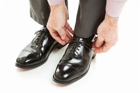 Man ties his shiney new black leather business shoes.  Isolated on white. Stock Photo - Budget Royalty-Free & Subscription, Code: 400-04119575