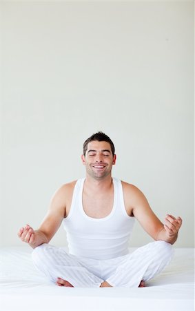 Attractive young man doing yoga in bed with copy-space Stock Photo - Budget Royalty-Free & Subscription, Code: 400-04119656