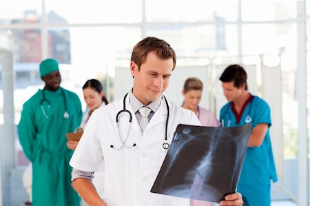 pupils and uniform and talking - Doctor examinig an X-ray with is team in the background Stock Photo - Budget Royalty-Free & Subscription, Code: 400-04119662