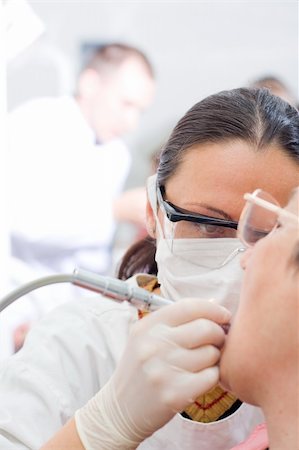 simsearch:400-04309650,k - A young dentist treating an old woman's teeth whit the turbine, a doctor in the background - part of a series. Stock Photo - Budget Royalty-Free & Subscription, Code: 400-04111635