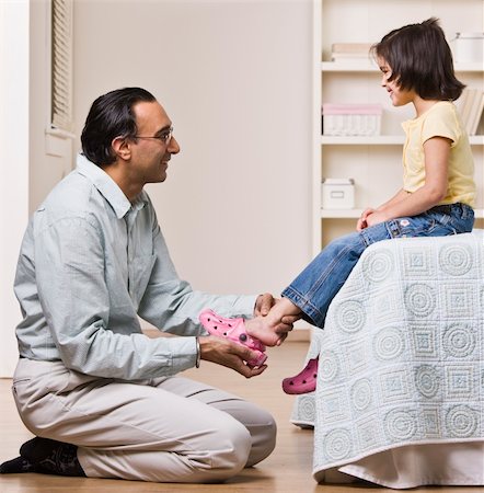 A father is helping his baby daughter with her shoes.  They are smiling and looking each other.  Square framed shot. Stock Photo - Budget Royalty-Free & Subscription, Code: 400-04124076