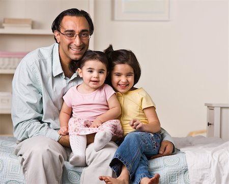 A father is sitting on a bed with his two young daughters.  They are smiling at the camera.  Horizontally framed shot. Stock Photo - Budget Royalty-Free & Subscription, Code: 400-04124073