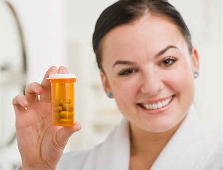 A woman is holding up a bottle of prescription medication and smiling at the camera.  Horizontally framed shot. Stock Photo - Budget Royalty-Free & Subscription, Code: 400-04124096