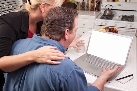 simsearch:400-05129327,k - Couple In Kitchen Using Laptop with Blank Screen. Screen can be easily used for your own message or picture. Stock Photo - Budget Royalty-Free & Subscription, Code: 400-04124312