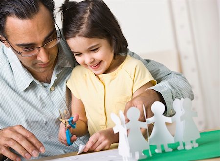 A father playing with his daughter.  He is helping her cut out paper dolls and she is smiling.  Horizontally framed shot. Stock Photo - Budget Royalty-Free & Subscription, Code: 400-04126325