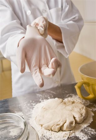 female pastry chef - Female chef putting on glove to complete pastry on counter. Vertical. Foto de stock - Super Valor sin royalties y Suscripción, Código: 400-04126398