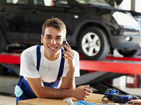 portrait young man mechanic - portrait of mechanic talking on mobile phone in auto repair shop. Looking at camera Stock Photo - Budget Royalty-Free & Subscription, Code: 400-04126658