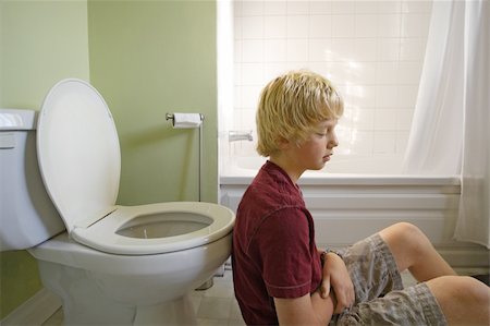 A young boy suffering with a stomachache, leaning up against a toilet. Shot with natural light coming through a window. Stock Photo - Budget Royalty-Free & Subscription, Code: 400-04128610