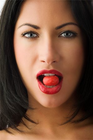 beautiful brunette with red lips and a red candy between teeth Stock Photo - Budget Royalty-Free & Subscription, Code: 400-04129510