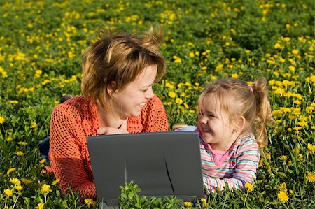 simsearch:400-06062677,k - Femme et petite fille portant sur le champ de fleurs de printemps à l'extérieur - s'amuser à l'aide d'un ordinateur portable Photographie de stock - Aubaine LD & Abonnement, Code: 400-04129545