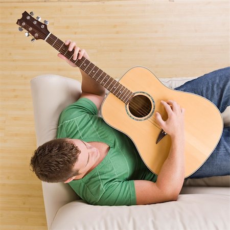 Man laying on couch playing guitar. Top view, square composition. Stock Photo - Budget Royalty-Free & Subscription, Code: 400-04120615