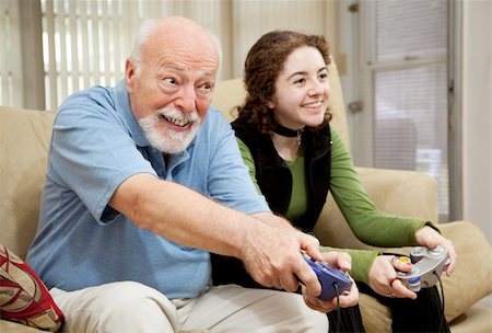 Senior man playing a video game with his teenage granddaughter. Photographie de stock - Aubaine LD & Abonnement, Code: 400-04121000