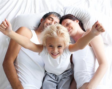 simsearch:400-04192370,k - Happy little girl on bed with her parents in the morning Fotografie stock - Microstock e Abbonamento, Codice: 400-04121406